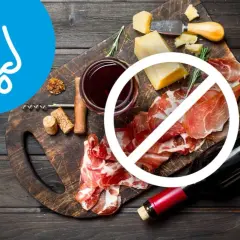 Deska serów i wędlin z winem, z symbolem zakazu. Wskazuje na dietę antyhistaminową.