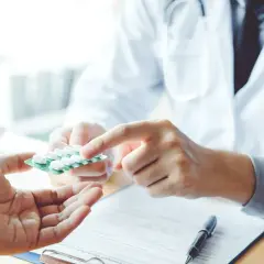 Lekarz podaje pacjentowi opakowanie tabletek, wyjaśniając, po jakim czasie działa antybiotyk.