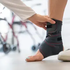 Fizjoterapeuta zakłada stabilizator na kostkę pacjenta. Badanie rezonans z kontrastem może pomóc w diagnozie.