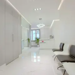 Nowoczesne wnętrze poczekalni kliniki estetycznej z białym marmurem i wygodnymi fotelami.