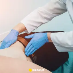 Lekarz w rękawiczkach bada pacjenta, wykonując badanie palpacyjne w celu wykluczenia skrętu jądra.