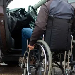 Osoba na wózku inwalidzkim wsiada do samochodu, co ułatwia ulga rehabilitacyjna na samochód.
