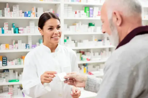 Farmaceutka podaje starszemu panu leki, doradzając mu atoris zamienniki.