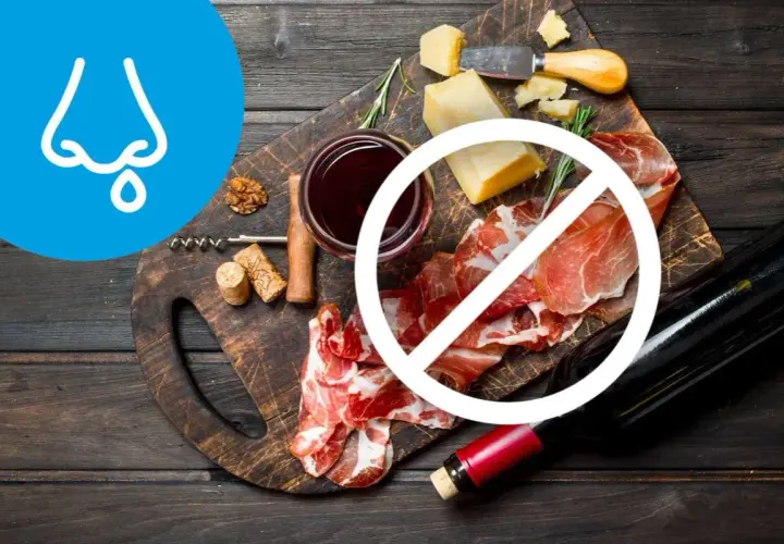 Deska serów i wędlin z winem, z symbolem zakazu. Wskazuje na dietę antyhistaminową.