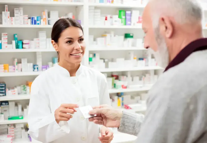 Farmaceutka podaje starszemu panu leki, doradzając mu atoris zamienniki.