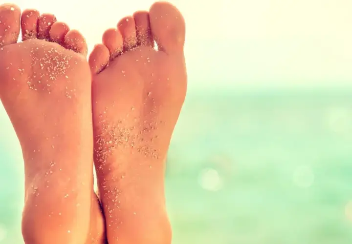 Stopy z piaskiem na plaży, z widocznym płaskostopiem.