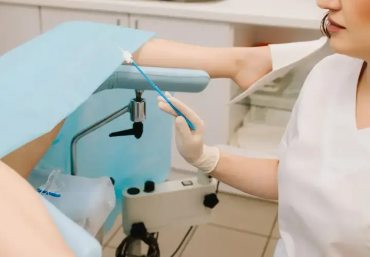 Lekarz przygotowuje się do ginekologicznego badania cytologicznego, pobierając wymaz do analizy.