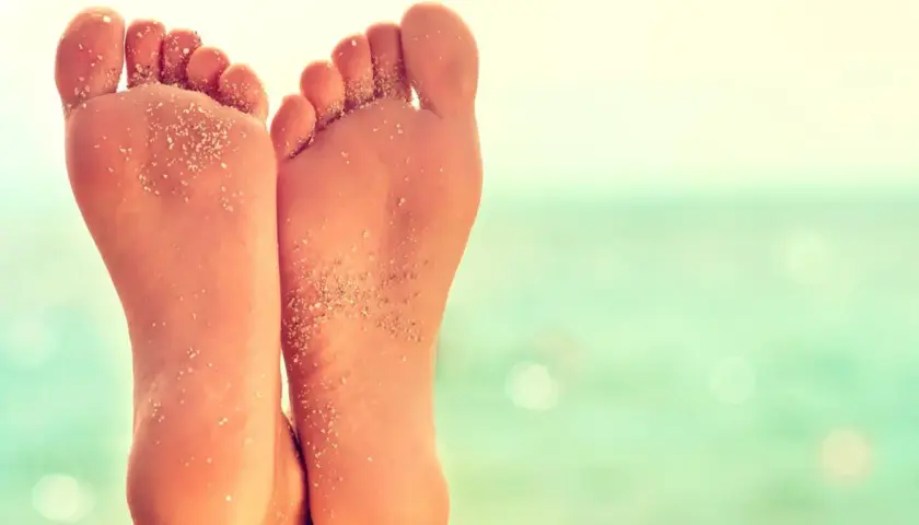 Stopy z piaskiem na plaży, z widocznym płaskostopiem.