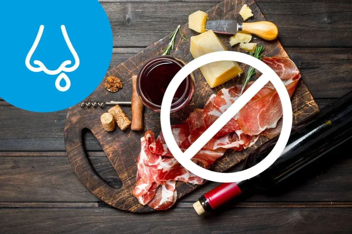 Deska serów i wędlin z winem, z symbolem zakazu. Wskazuje na dietę antyhistaminową.