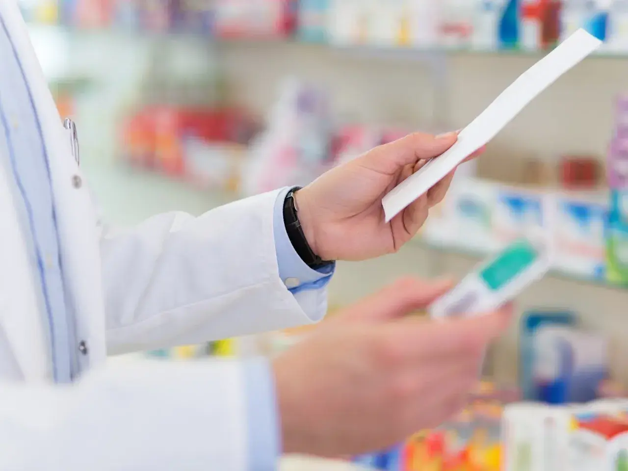 Farmaceuta w białym fartuchu trzyma receptę i opakowanie leku, być może Laxigen, w aptece.