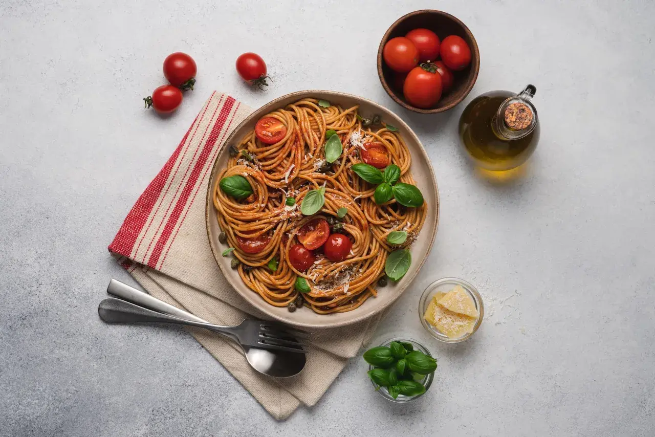 Pyszne spaghetti z pomidorami i bazylią, idealne na dietę SIBO. Oliwa, parmezan i świeże zioła dopełniają danie.