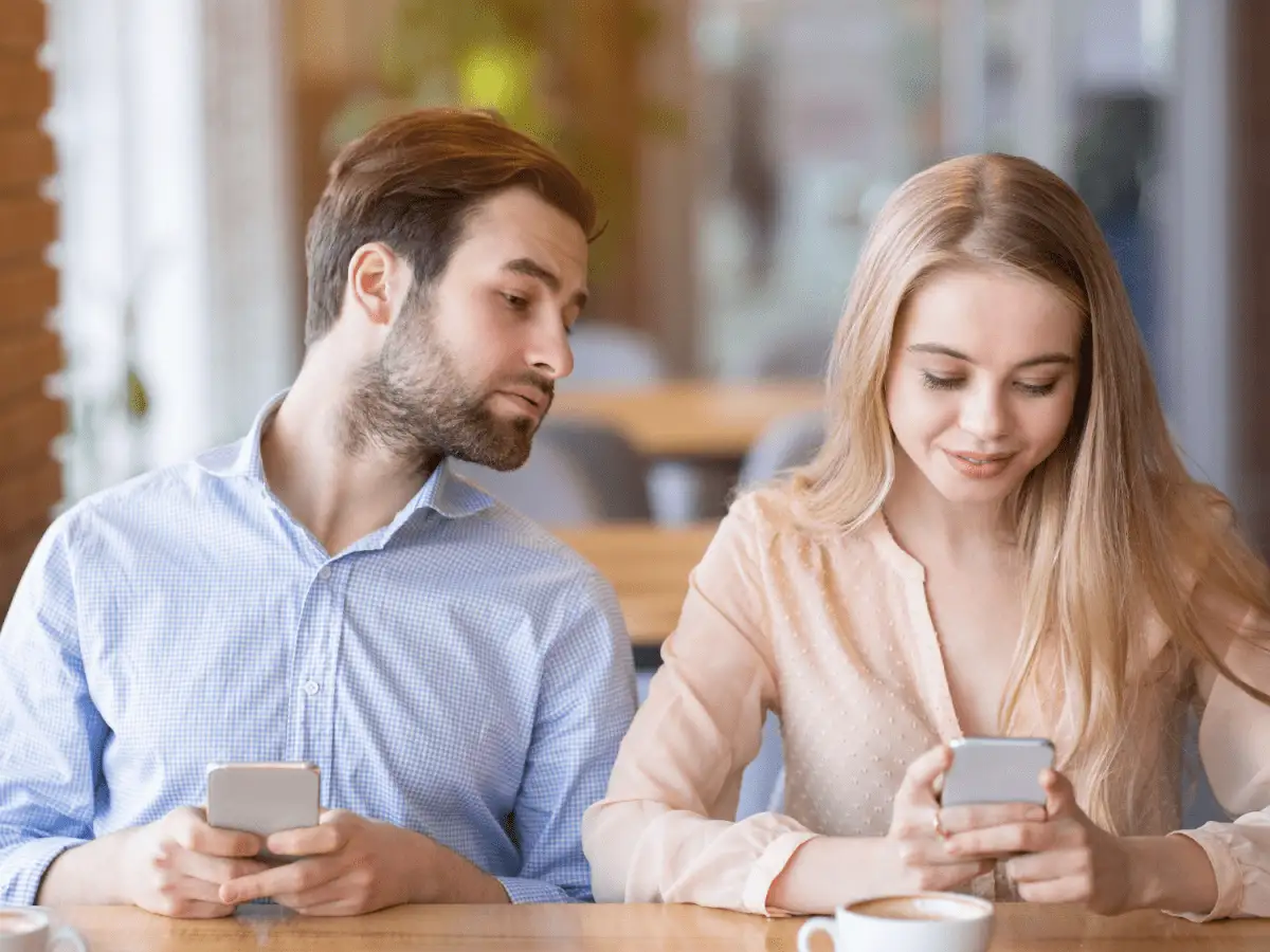 Mężczyzna z zazdrością spogląda na telefon kobiety, objawy zespołu Otella.