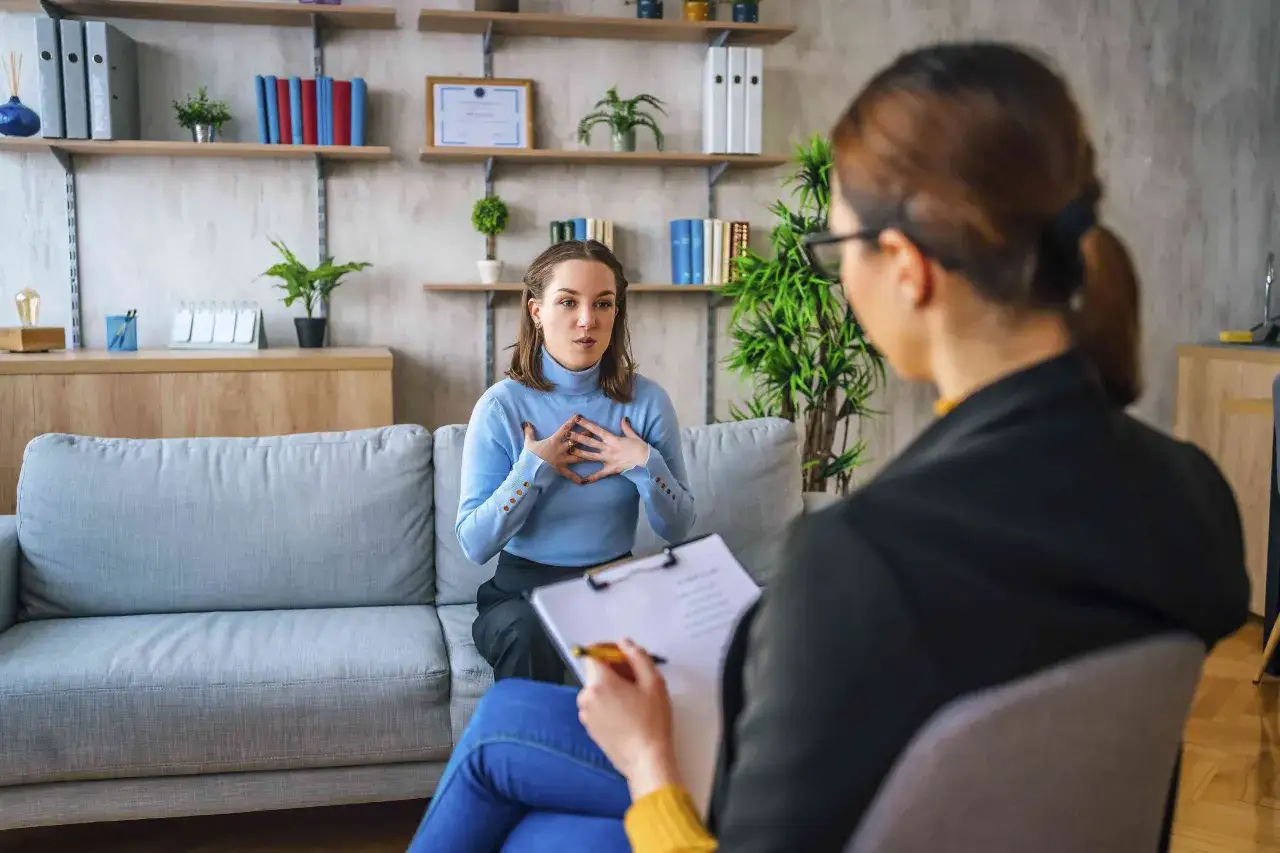 Kobieta opowiada o swoich problemach podczas sesji terapii CBT. Terapeuta notuje.