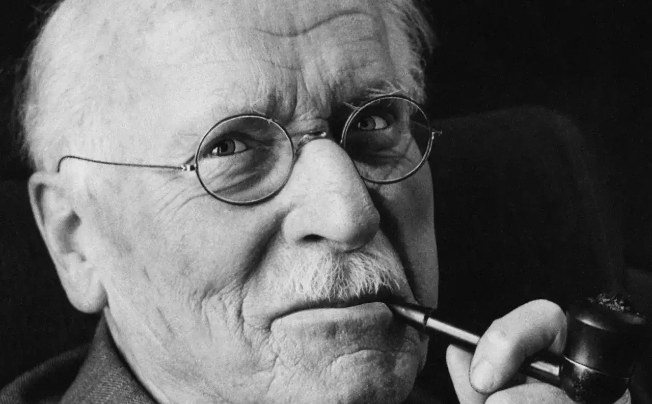 Carl Gustav Jung, zamyślony, z fajką w ustach, w okularach.